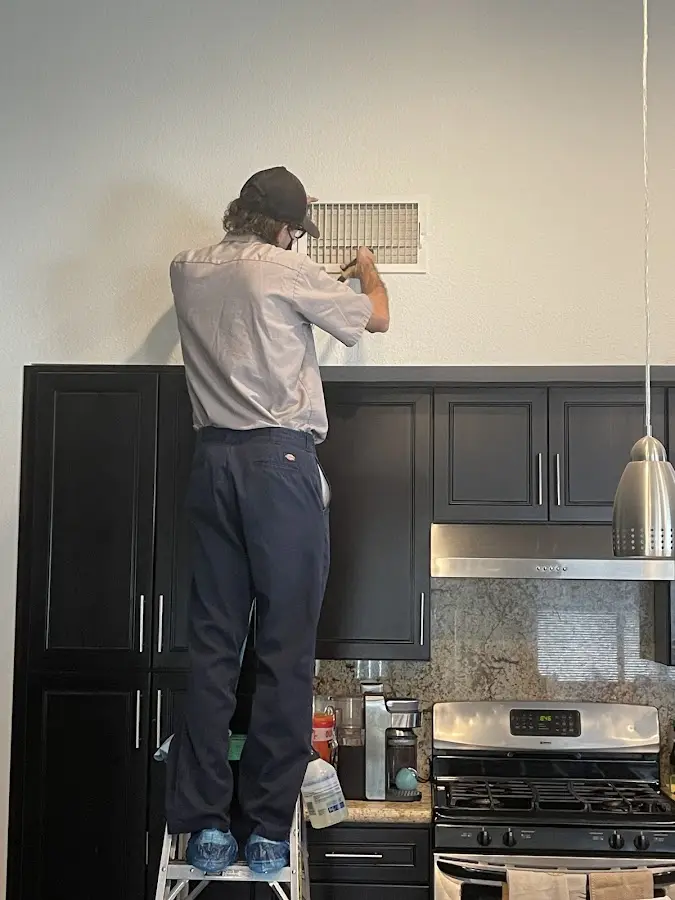 Technician inspecting an air vent during HVAC service in Blythe